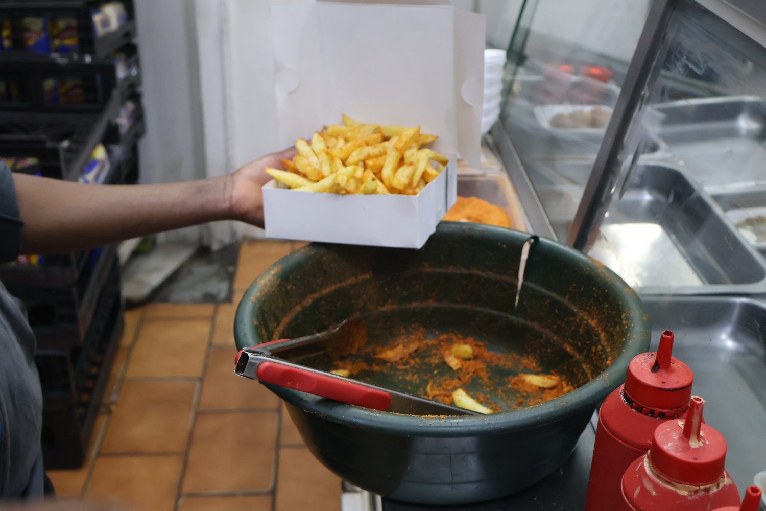 A fresh box of seasoned hot chips being served from the take-away kitchen